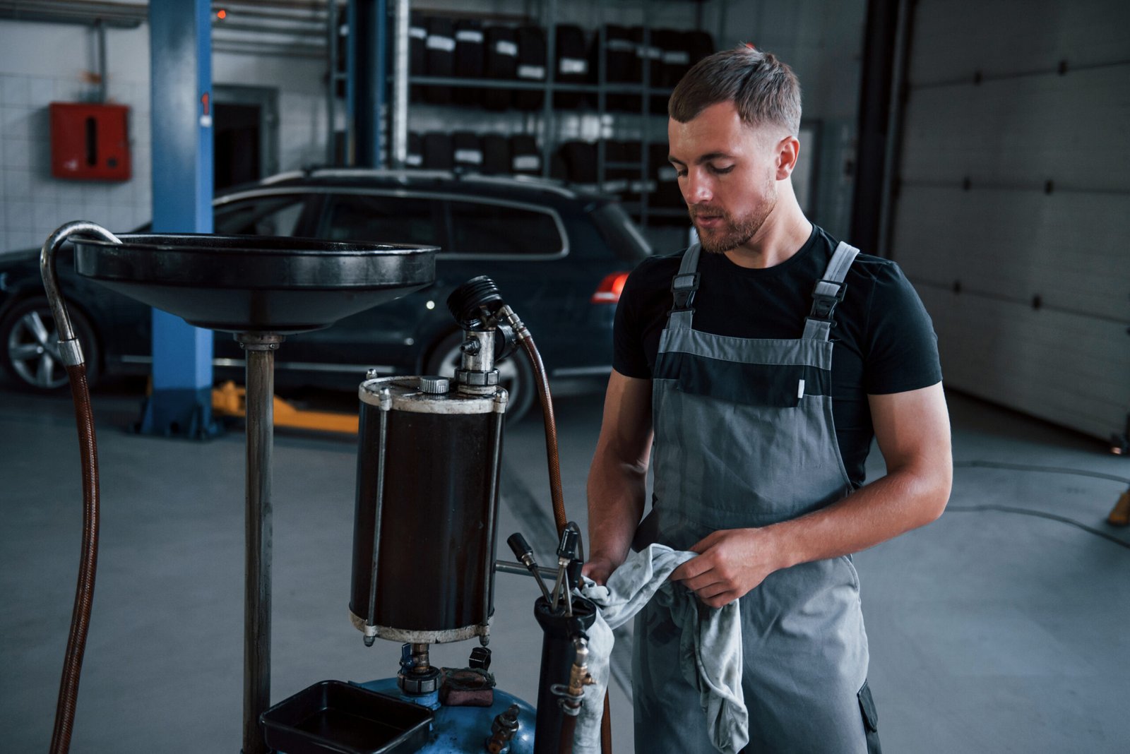 Everything is almost ready. Male mechanic use special device to repair broken automobile in garage.